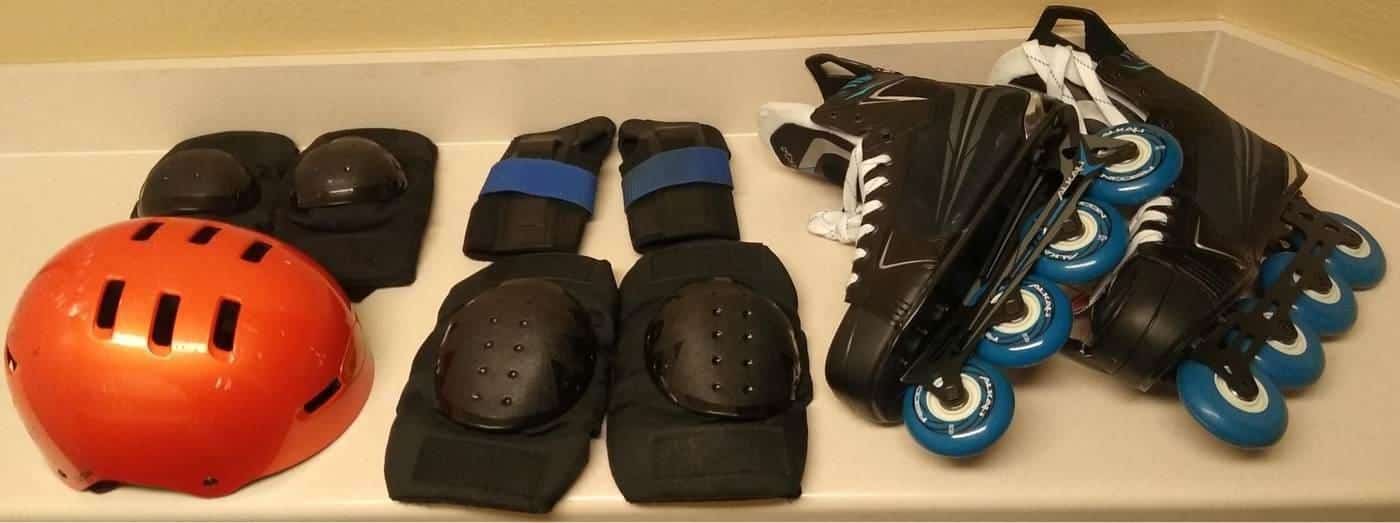 A helmet, wrist guards, knee and elbow pads laid out with inline skates